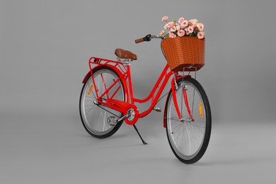 Photo of Bicycle with basket of beautiful flowers on grey background