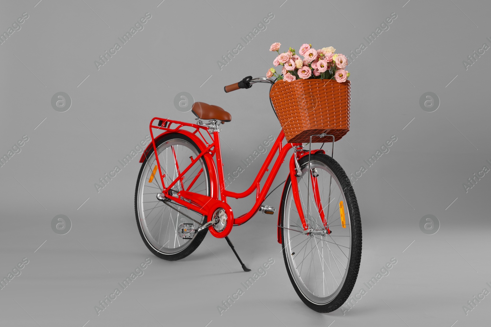 Photo of Bicycle with basket of beautiful flowers on grey background