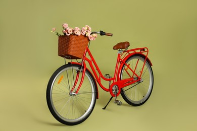 Photo of Bicycle with basket of beautiful flowers on green background
