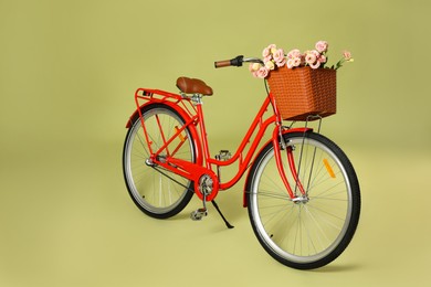 Photo of Bicycle with basket of beautiful flowers on green background