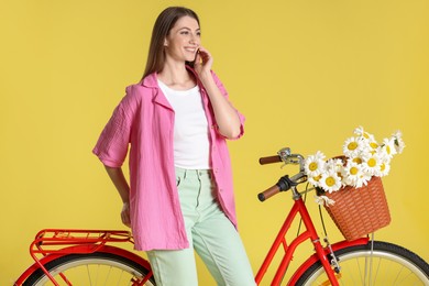 Photo of Smiling woman and bicycle with basket of flowers against light green background