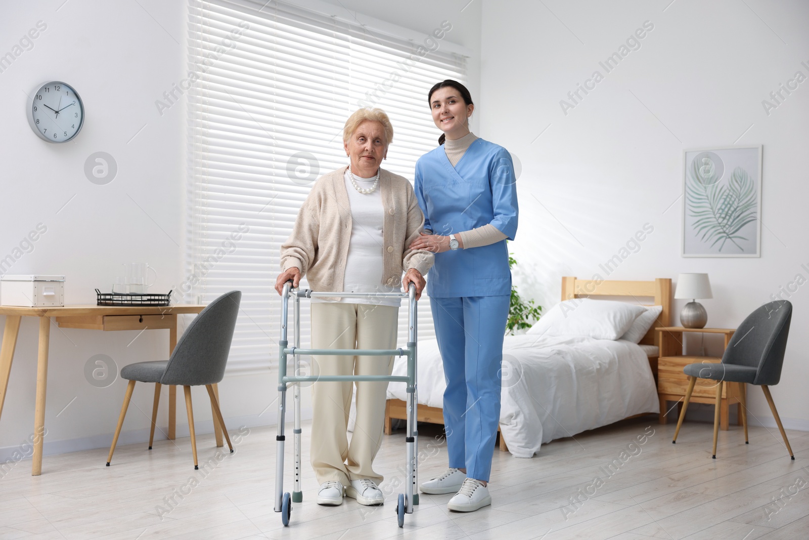 Nurse assisting senior woman with walking frame indoors. Home health care service Photo of Nurse assisting senior woman with walking frame indoors. Home health care service