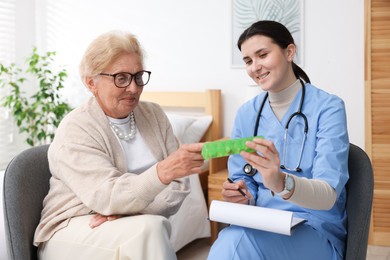 Photo of Nurse giving pills to senior woman indoors. Home health care service