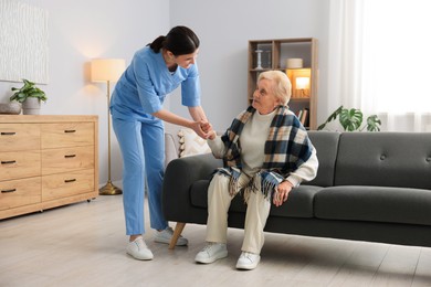 Photo of Nurse assisting senior woman indoors. Home health care service