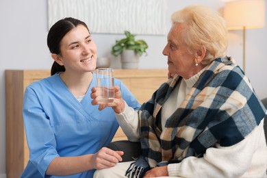 Photo of Nurse assisting senior woman indoors. Home health care service