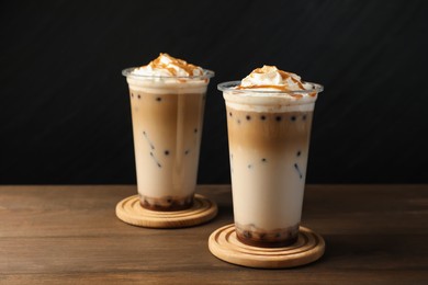Photo of Tasty milk bubble tea in plastic cups on wooden table