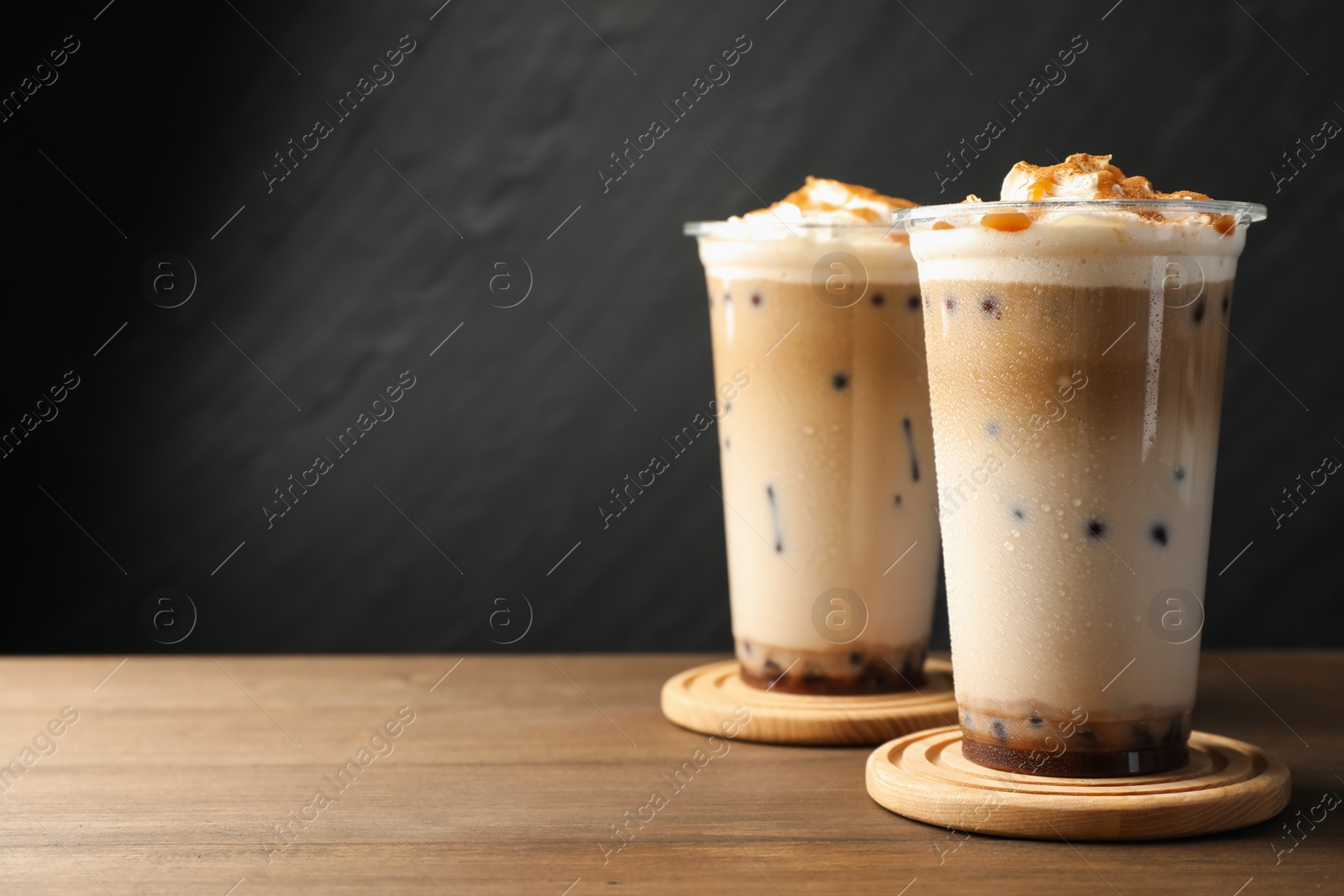 Tasty milk bubble tea in plastic cups on wooden table, closeup. Space for text Photo of Tasty milk bubble tea in plastic cups on wooden table, closeup. Space for text