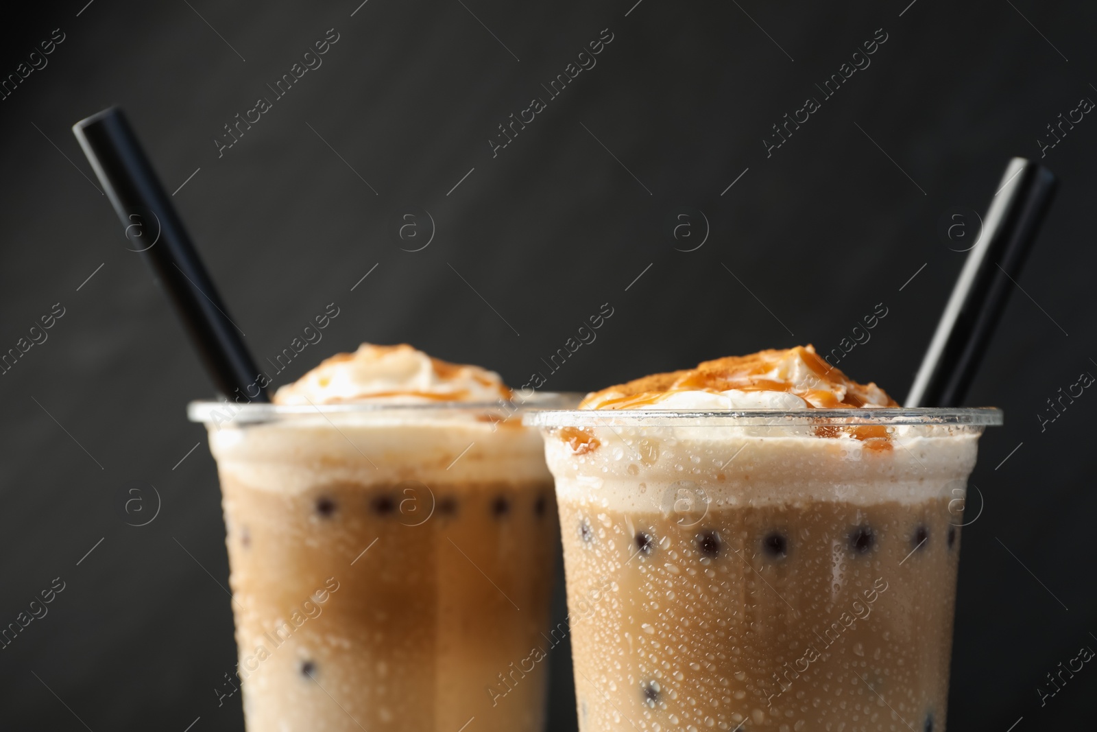Tasty milk bubble tea in plastic cups on black background, closeup Photo of Tasty milk bubble tea in plastic cups on black background, closeup