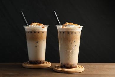 Photo of Tasty milk bubble tea in plastic cups on wooden table
