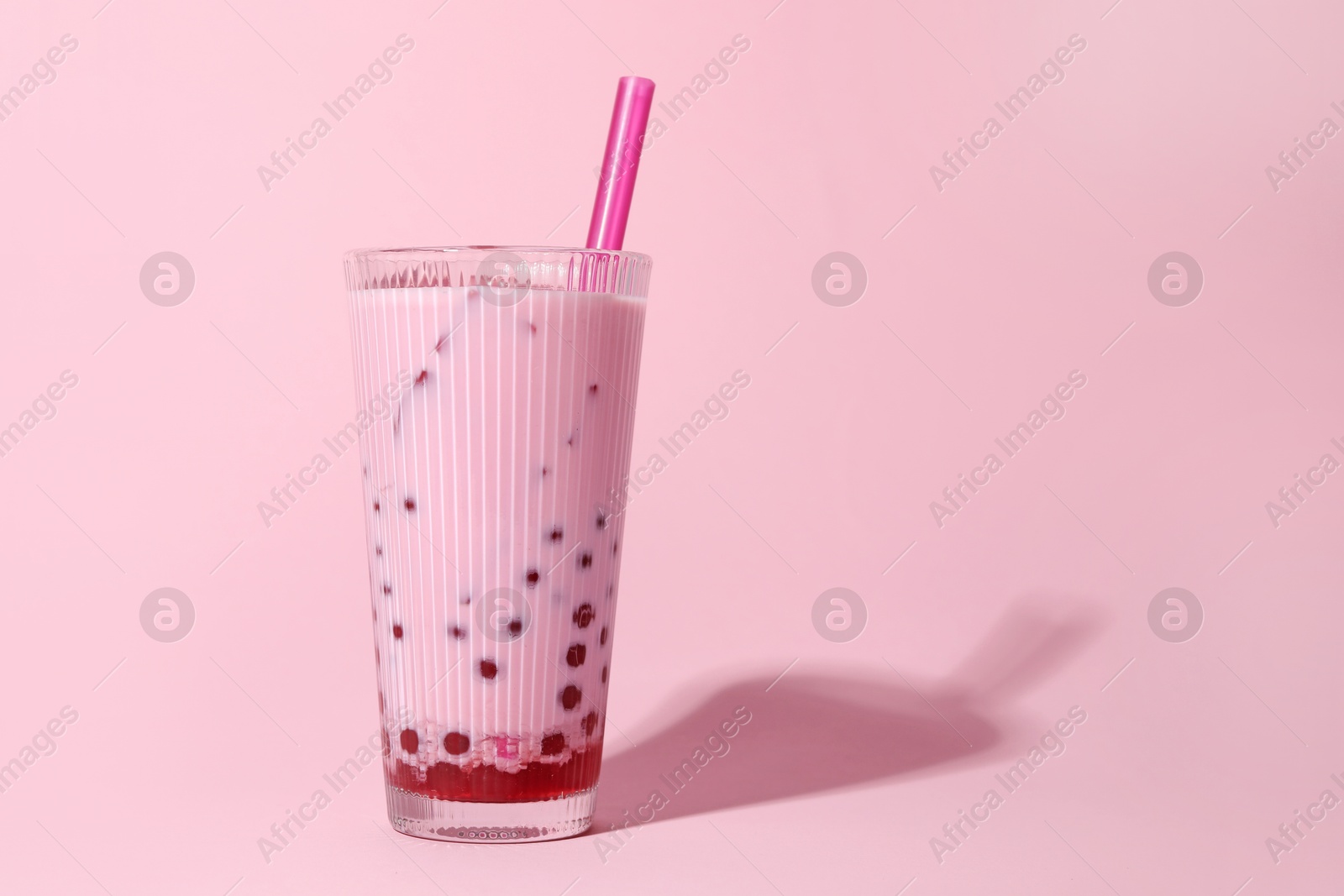 Tasty milk bubble tea in glass on pink background, space for text Photo of Tasty milk bubble tea in glass on pink background, space for text