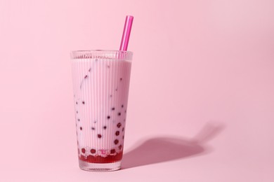 Photo of Tasty milk bubble tea in glass on pink background, space for text