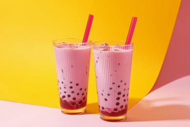 Photo of Tasty milk bubble tea in glasses on color background