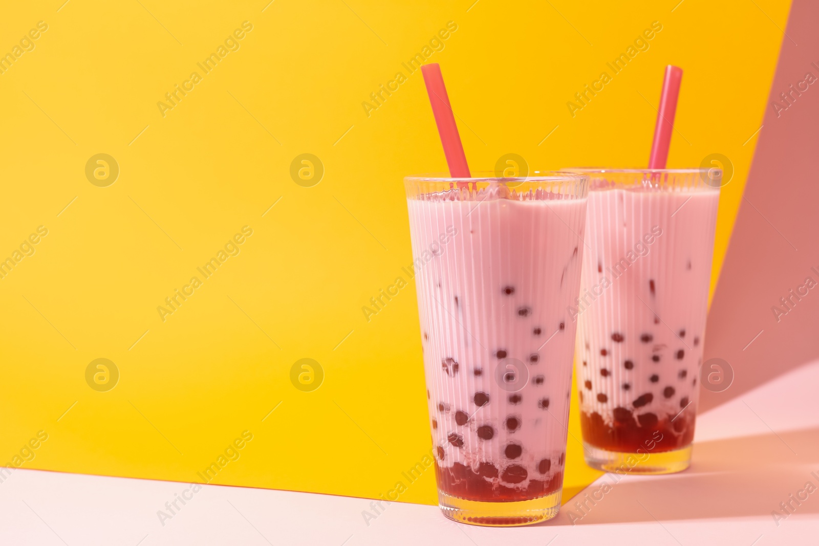 Tasty milk bubble tea in glasses on color background, space for text Photo of Tasty milk bubble tea in glasses on color background, space for text