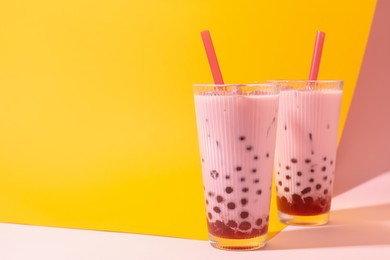 Photo of Tasty milk bubble tea in glasses on color background, space for text