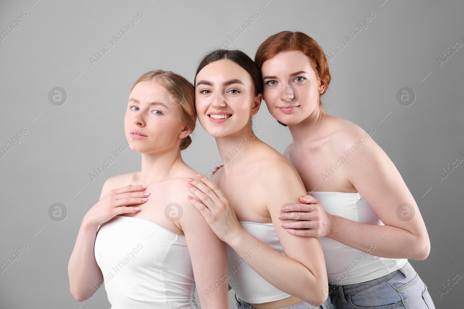 Beautiful women with different hair colors on grey background Photo of Beautiful women with different hair colors on grey background