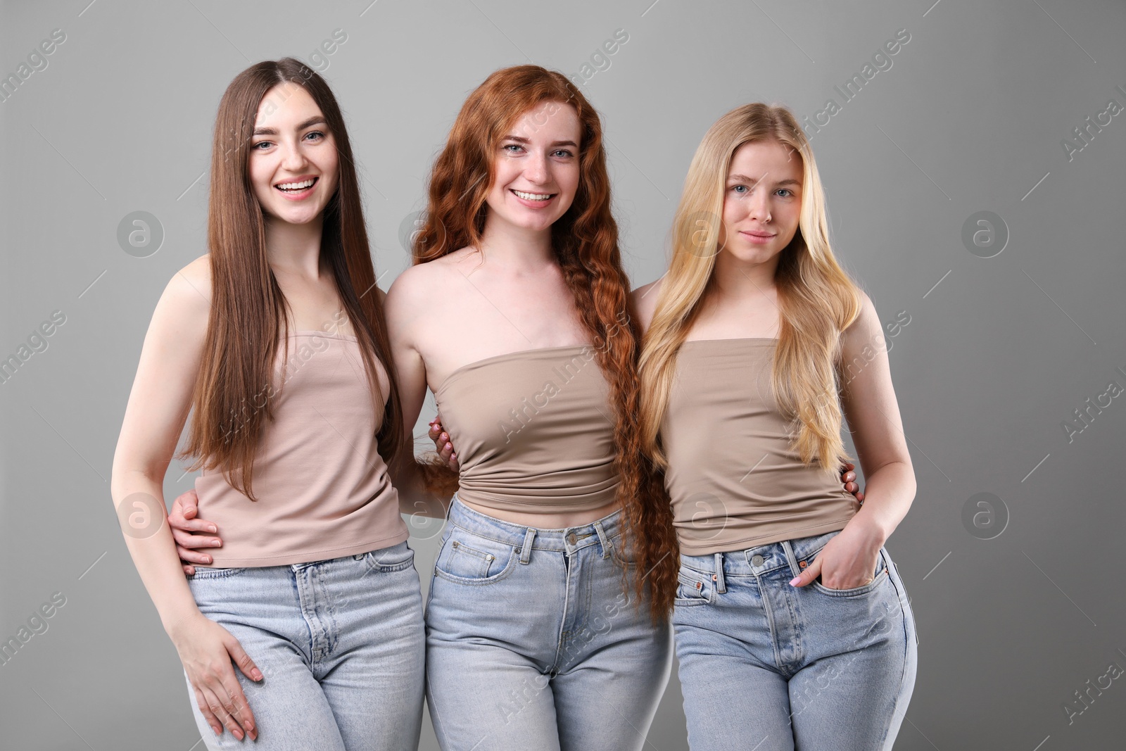 Beautiful women with different hair colors on grey background Photo of Beautiful women with different hair colors on grey background
