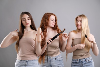 Photo of Beautiful women with different hair colors holding curling iron, shampoo and brush on grey background