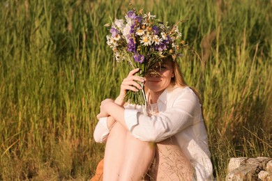 Photo of Woman with bouquet of beautiful wildflowers outdoors on sunny day