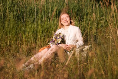 Photo of Woman with bouquet of beautiful wildflowers outdoors on sunny day