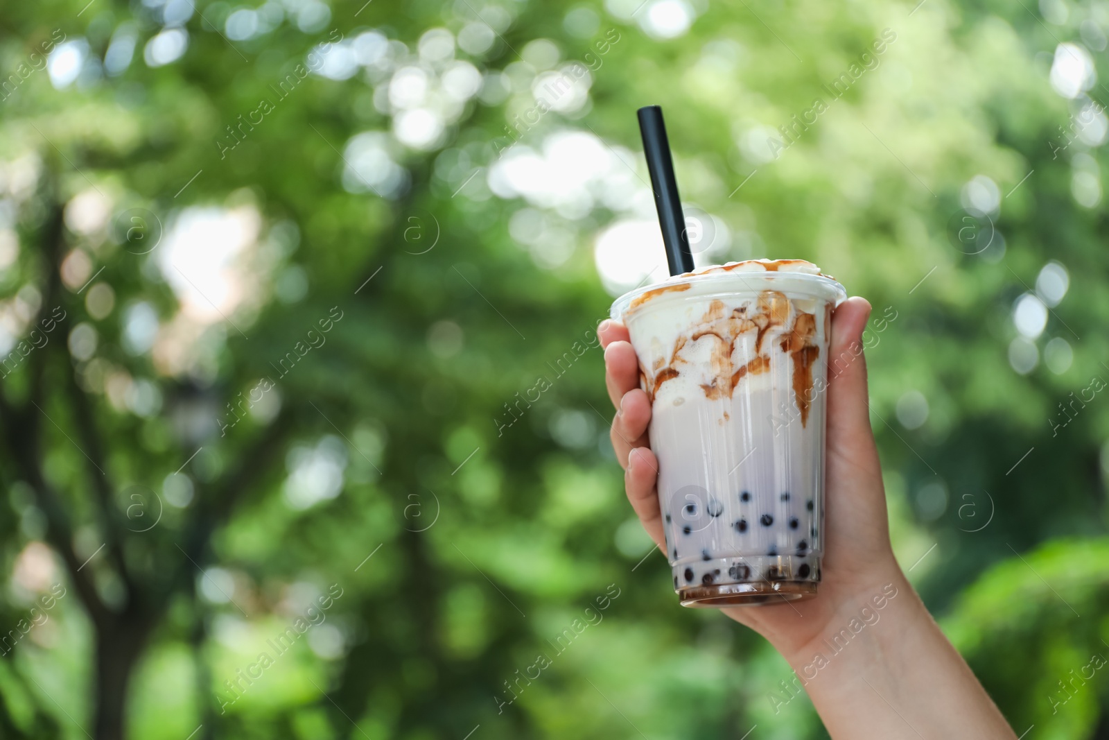 Woman with tasty milk bubble tea in plastic cup outdoors, closeup. Space for text Photo of Woman with tasty milk bubble tea in plastic cup outdoors, closeup. Space for text