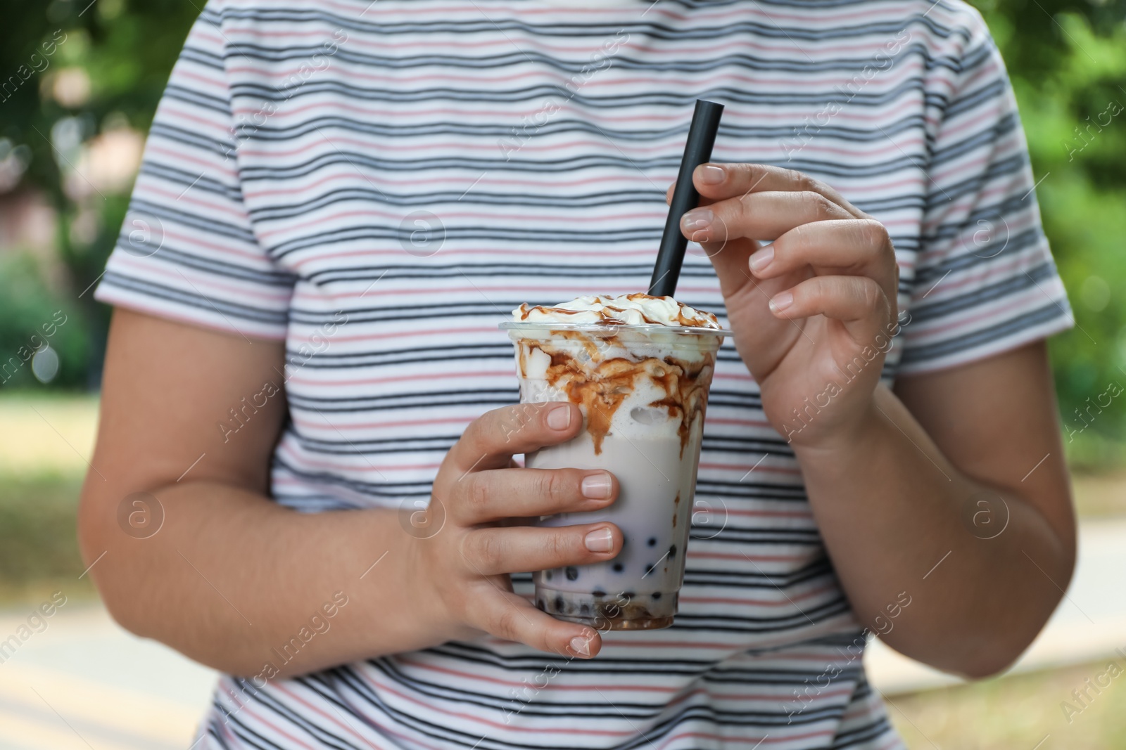 Woman with tasty milk bubble tea in plastic cup outdoors, closeup Photo of Woman with tasty milk bubble tea in plastic cup outdoors, closeup