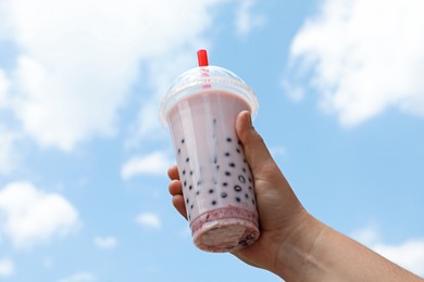 Photo of Woman with tasty milk bubble tea in plastic cup outdoors, closeup