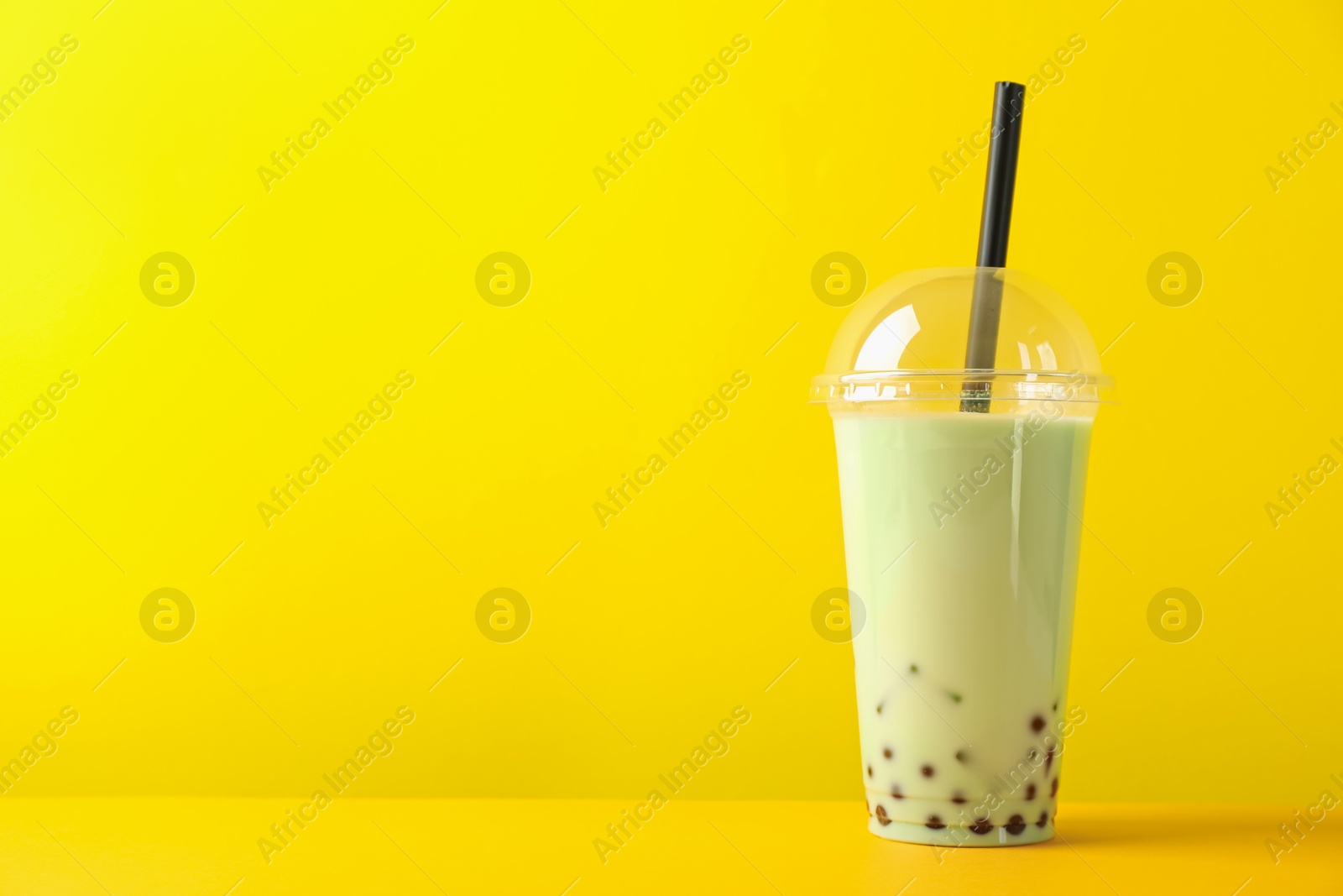 Tasty milk bubble tea in plastic cup on yellow background. Space for text Photo of Tasty milk bubble tea in plastic cup on yellow background. Space for text