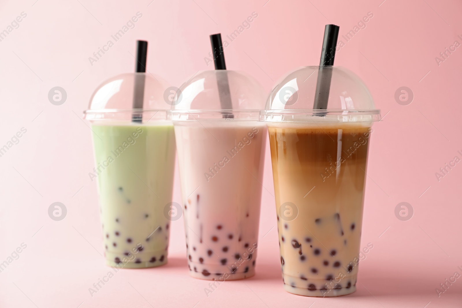 Tasty milk bubble tea in plastic cups on pink background Photo of Tasty milk bubble tea in plastic cups on pink background