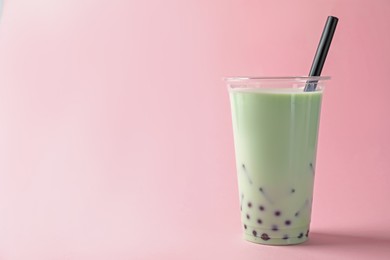 Photo of Tasty milk bubble tea in plastic cup on pink background. Space for text