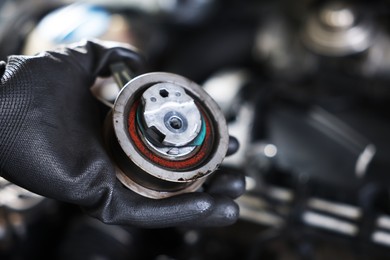 Photo of Auto part. Professional mechanic with idler-wheel near open hood of car indoors, closeup. Space for text