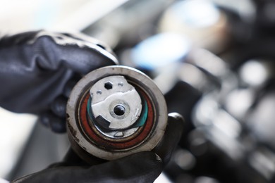 Photo of Auto part. Professional mechanic with idler-wheel near open hood of car indoors, closeup. Space for text