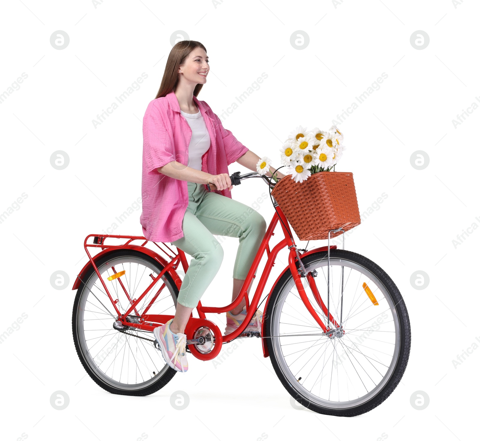 Photo of Smiling woman riding bicycle with basket of flowers against white background