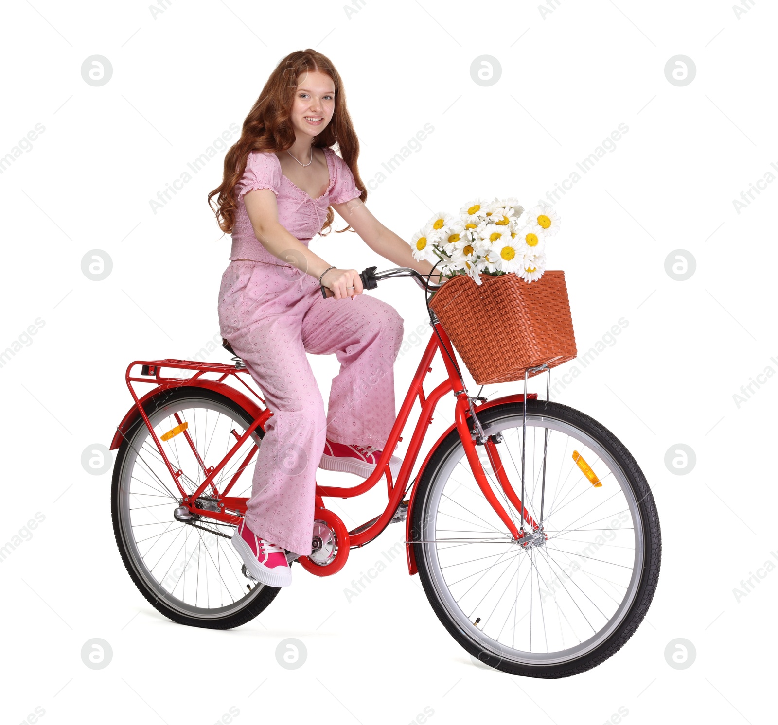 Smiling teenage girl riding bicycle with basket of flowers against white background Photo of Smiling teenage girl riding bicycle with basket of flowers against white background