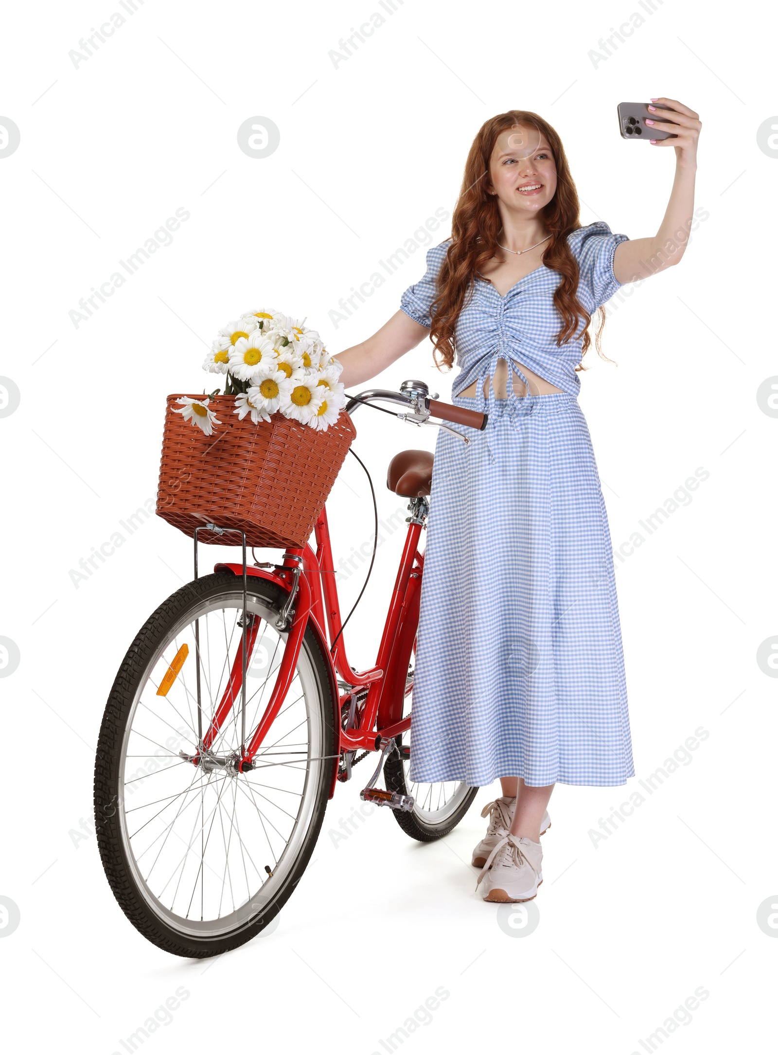 Smiling teenage girl taking selfie and bicycle with basket of flowers against white background Photo of Smiling teenage girl taking selfie and bicycle with basket of flowers against white background
