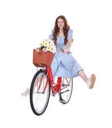 Photo of Smiling teenage girl riding bicycle with basket of flowers against white background