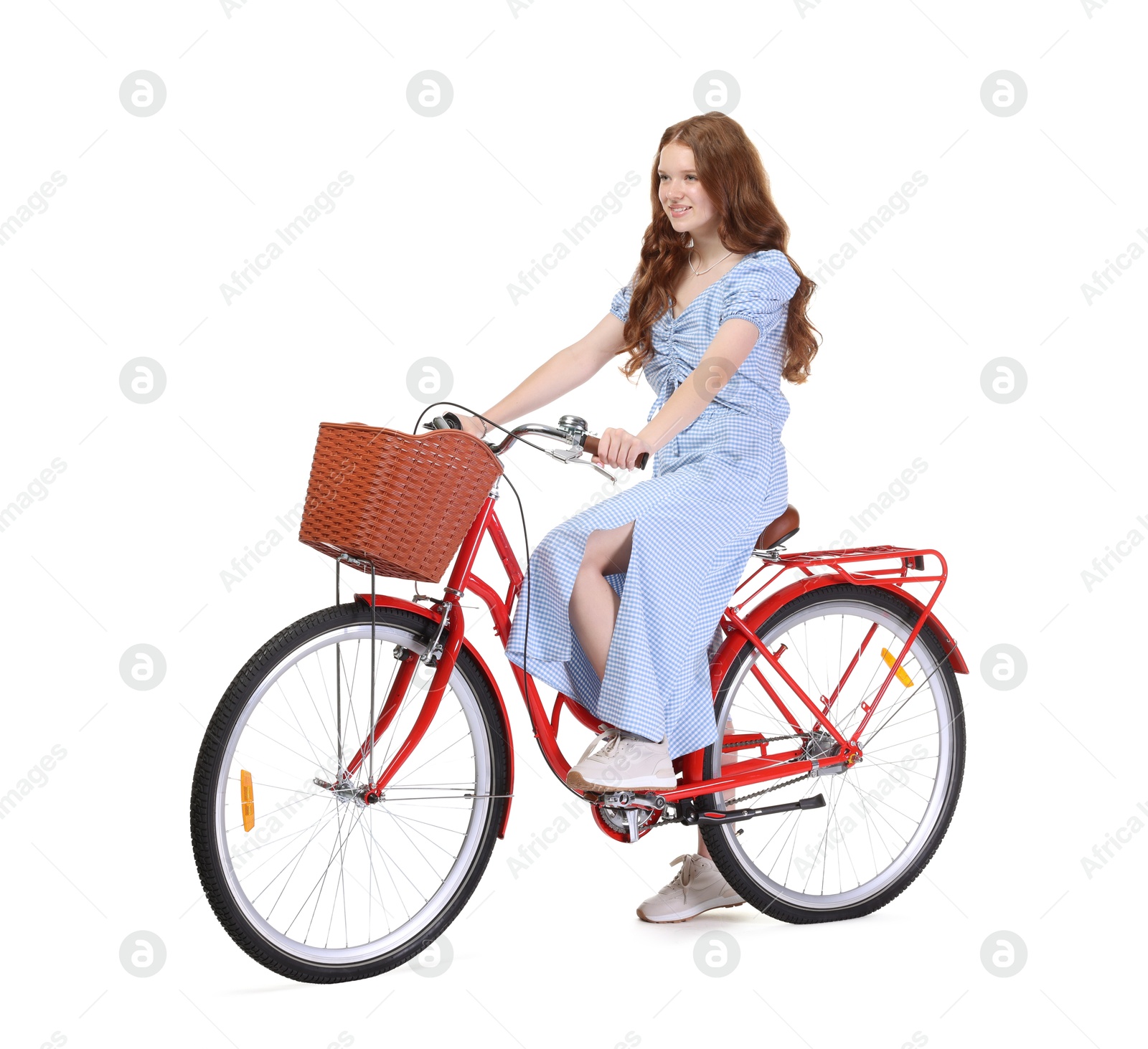 Smiling teenage girl posing on bicycle with basket against white background Photo of Smiling teenage girl posing on bicycle with basket against white background