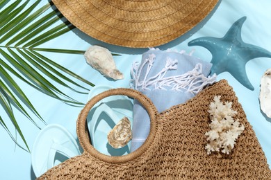 Photo of Flat lay composition with different beach accessories and palm leaf on light blue background