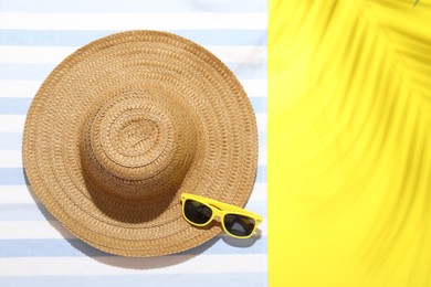 Photo of Beach towel, straw hat and sunglasses on yellow background, top view. Space for text