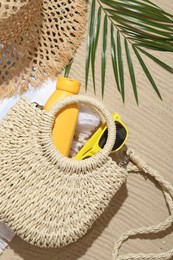 Photo of Different beach accessories and palm leaf on sand outdoors, flat lay
