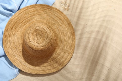 Photo of Beach towel, straw hat and seashell on sand outdoors, flat lay. Space for text