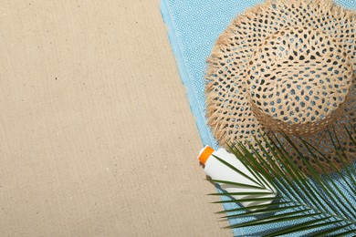 Photo of Beach towel, straw hat, sunscreen product and palm leaf on sand outdoors, flat lay. Space for text