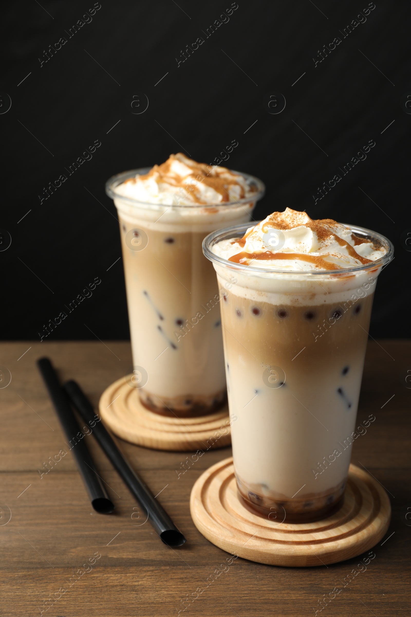 Tasty milk bubble tea in plastic cups on wooden table Photo of Tasty milk bubble tea in plastic cups on wooden table
