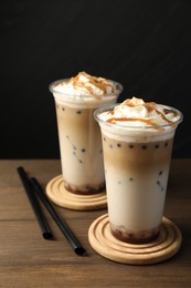 Photo of Tasty milk bubble tea in plastic cups on wooden table