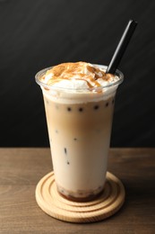 Photo of Tasty milk bubble tea in plastic cup on wooden table, closeup