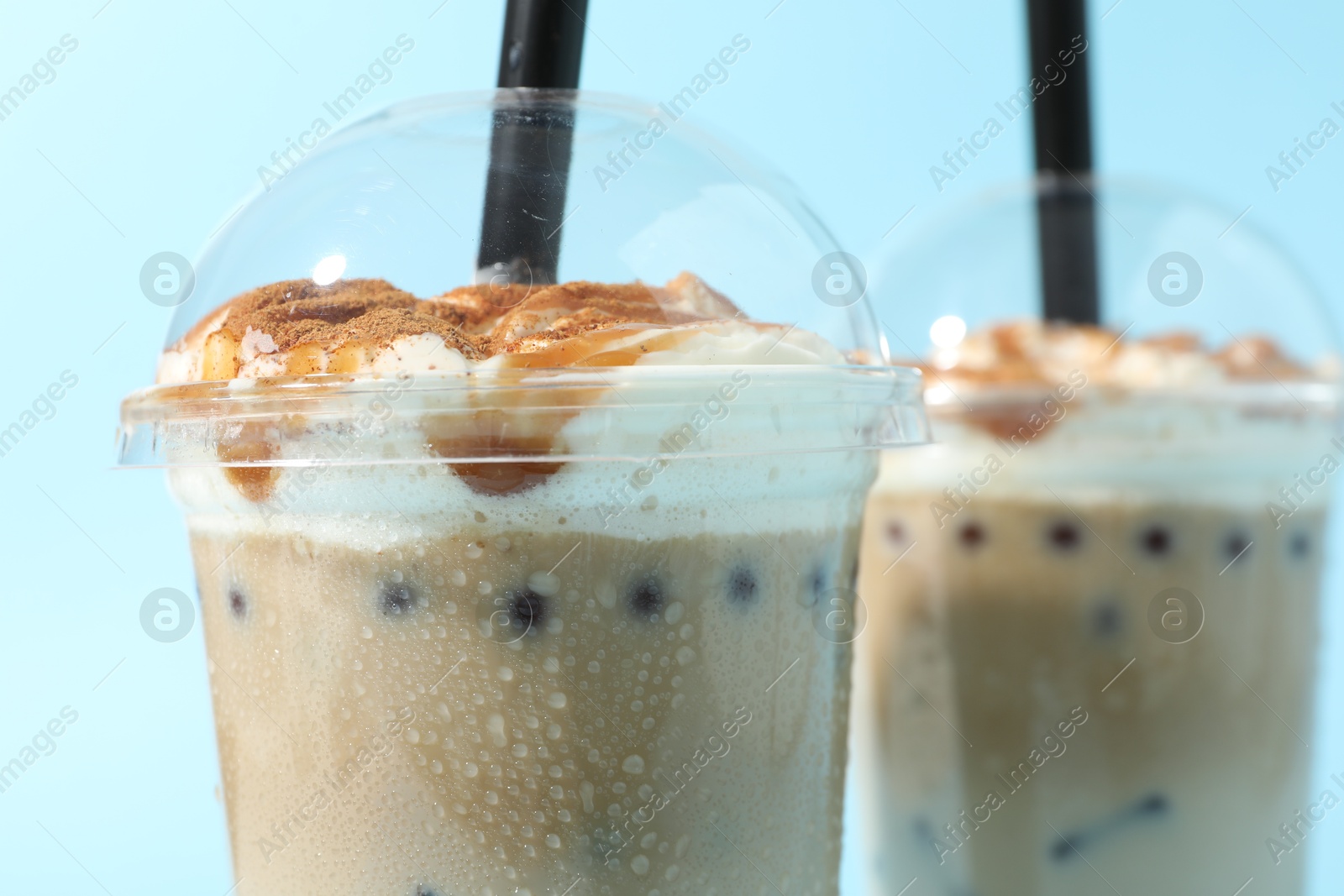 Tasty milk bubble tea in plastic cups on light blue background, closeup Photo of Tasty milk bubble tea in plastic cups on light blue background, closeup