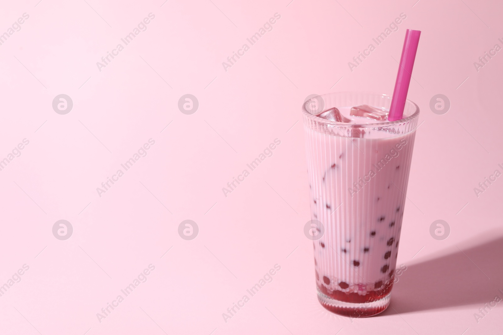 Tasty milk bubble tea in glass on pink background, space for text Photo of Tasty milk bubble tea in glass on pink background, space for text
