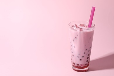 Photo of Tasty milk bubble tea in glass on pink background, space for text
