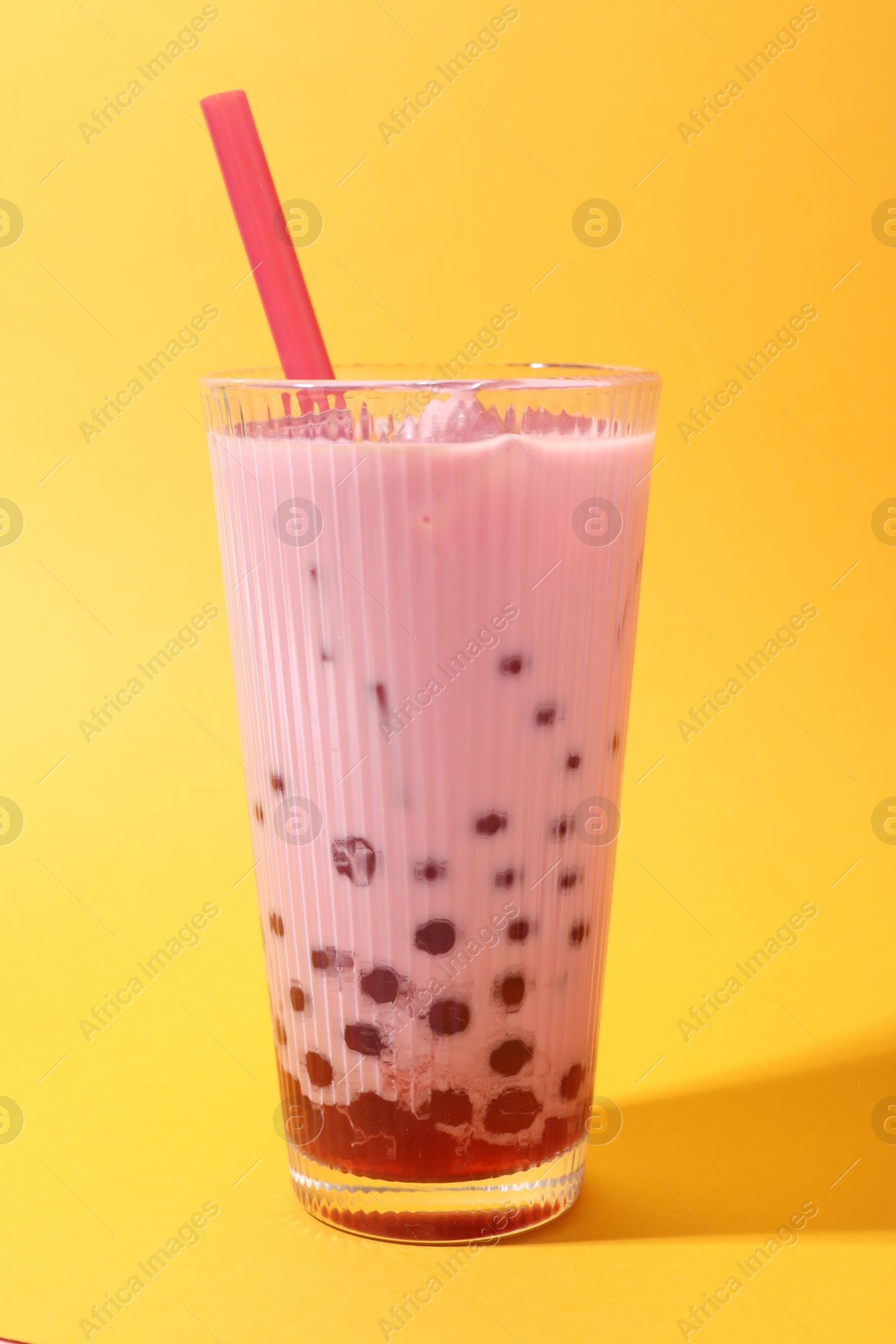 Tasty milk bubble tea in glass on orange background Photo of Tasty milk bubble tea in glass on orange background