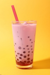 Photo of Tasty milk bubble tea in glass on orange background