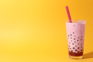 Photo of Tasty milk bubble tea in glass on orange background, space for text